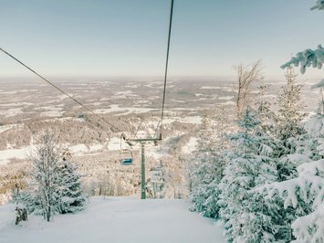 Winterurlaub in Bayern im BERGEBLICK Blick auf schneebedeckten Skilift und verschneite Bäume im Winter