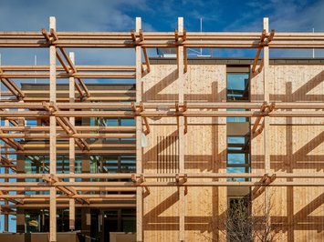 Dein Job in Bad Tölz/Bayern Modernes Gebäude mit sichtbarem Holzrahmen und klaren Linien vor blauem Himmel