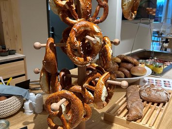 Board and restaurants Pretzels hanging on a wooden stand at a breakfast buffet with various breads