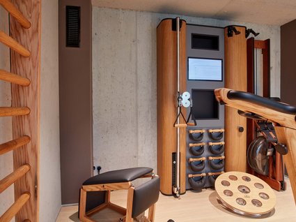 Your active holiday in Bavaria Modern gym room with wooden exercise machines and rowing machine by concrete wall