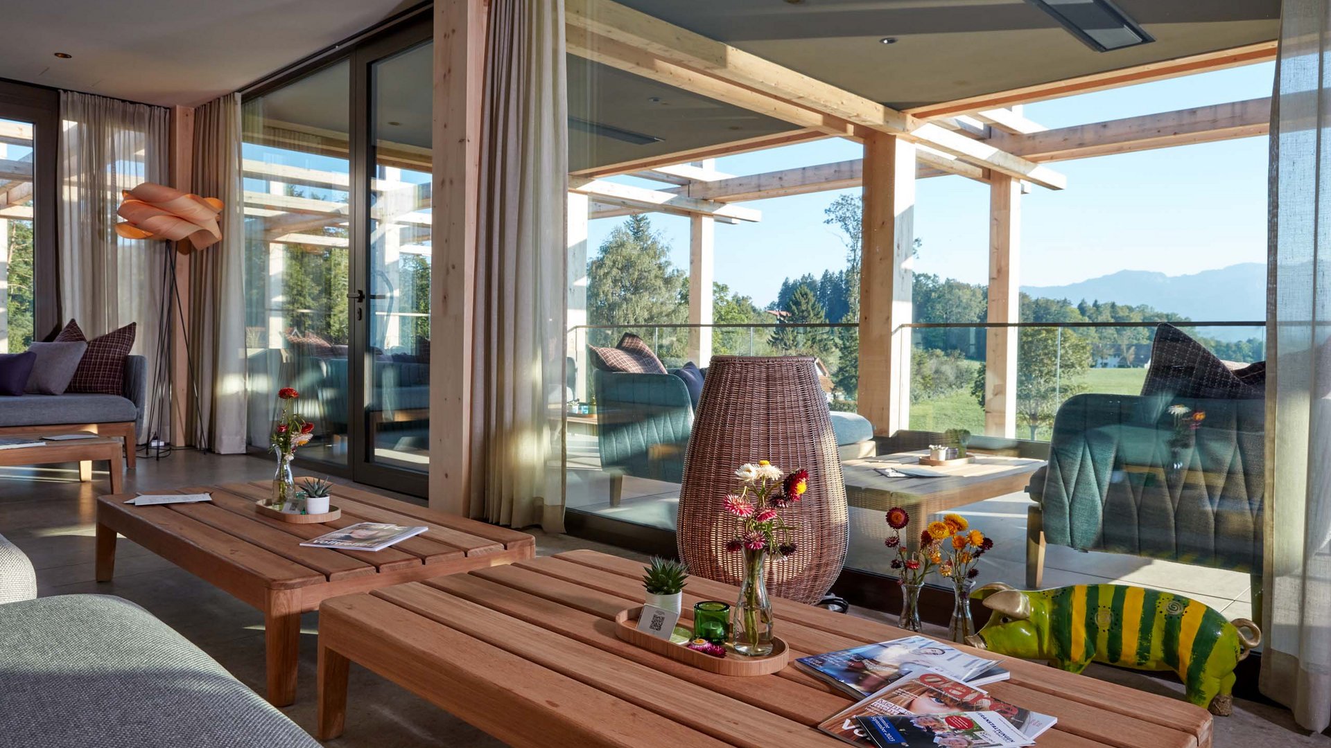 Deine Lounge für Business & Genuss Gemütlicher Wohnbereich mit Holztischen, Dekoration und Ausblick auf Balkon und Natur