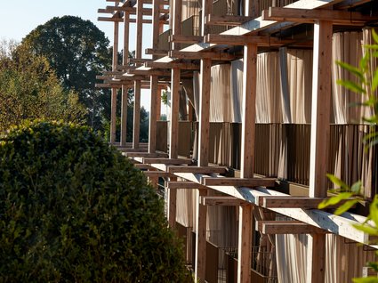 A holiday amidst nature in Germany Facade with wooden frames and curtains beside green bushes and trees