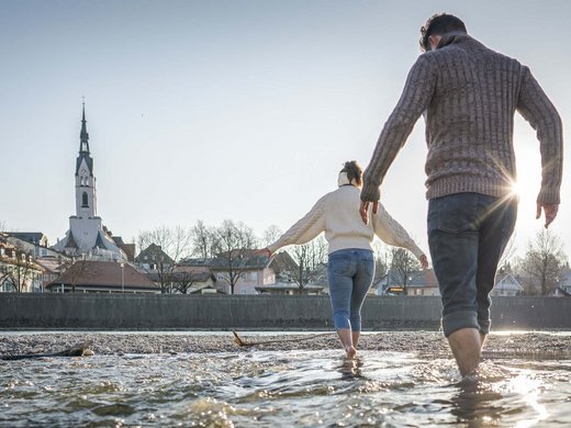 Holiday at BERGEBLICK in Bad Tölz Couple wading barefoot in river near town with church on sunny day