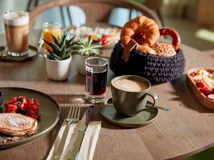 Bad Tölz: Hotel mit regionalem Frühstück Frühstückstisch mit Kaffee, Brötchen, Pancakes und verschiedenen Getränken