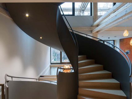 A holiday amidst nature in Germany Modern wooden spiral staircase in a bright room with large windows