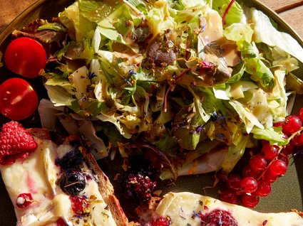 Bad Tölz: Hotel mit regionalem Frühstück Salat mit Käsebrot und Beeren auf einem Teller, daneben ein Glas Bier