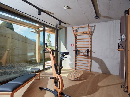 Your active holiday in Bavaria Bright gym room with wooden exercise bike, bench, and climbing wall