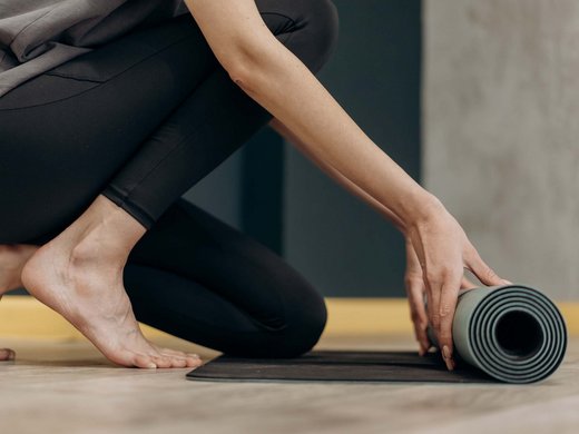 Dein Sporthotel in Bayern – Aktivurlaub im BERGEBLICK Person rollt eine Yogamatte in sportlicher Kleidung zusammen