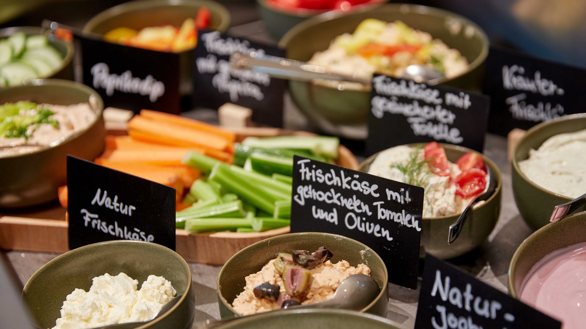Board and restaurants Various cream cheeses and vegetables in bowls with labels on a buffet