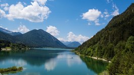 Your active summer holiday in Bavaria Mountain lake with forested slopes under a blue sky with clouds